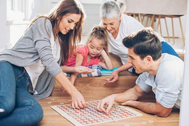 Multi-generation family playing a board game on the floor at home