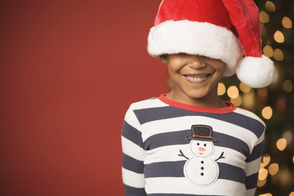 African boy smiling and wearing Santa Claus hat