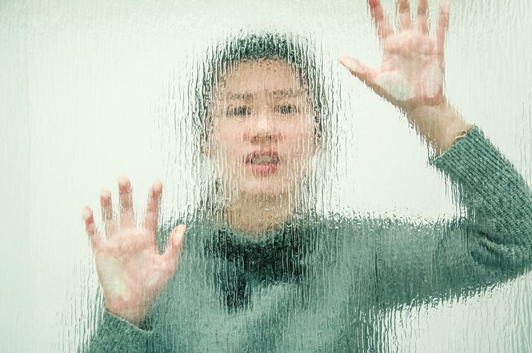 A woman stands before a glass wall, symbolizing self-reflection and the importance of recognizing one's attitude
