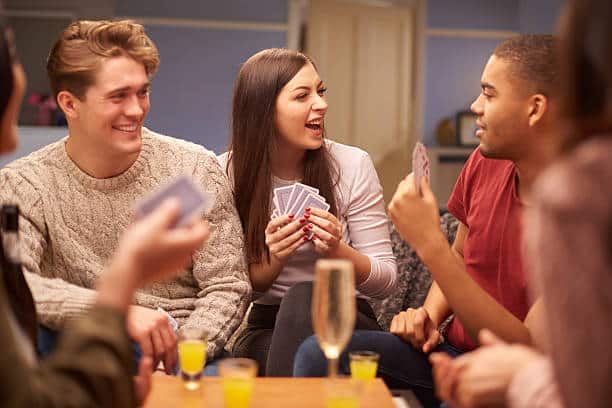 A group of friends engaged in a card game at a lively party