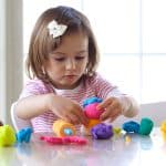 A young girl molding play dough, developing motor skills through creative play
