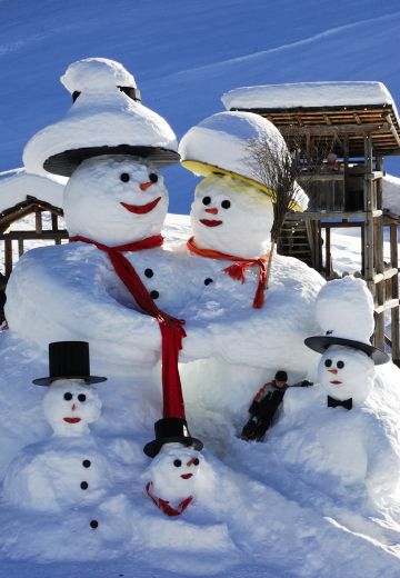 A delightful family of snowmen standing together in the snow, bringing joy and warmth to the winter landscape