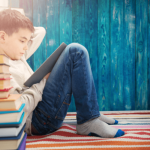 A young boy engrossed in a book while sitting on a rug, exploring the world of literature