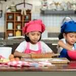 Two girls joyfully baking a cake with kid-friendly kitchen gadgets and tools