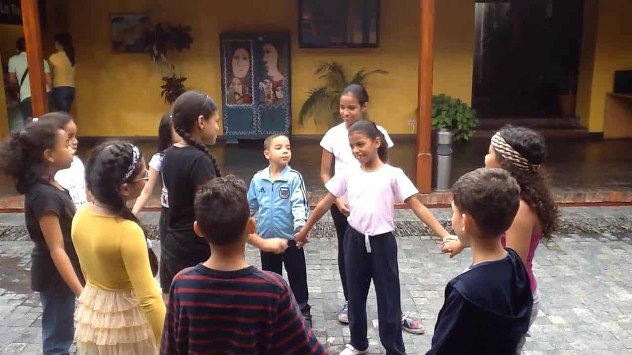 A man leading a group of children in a physical activity, holding hands together