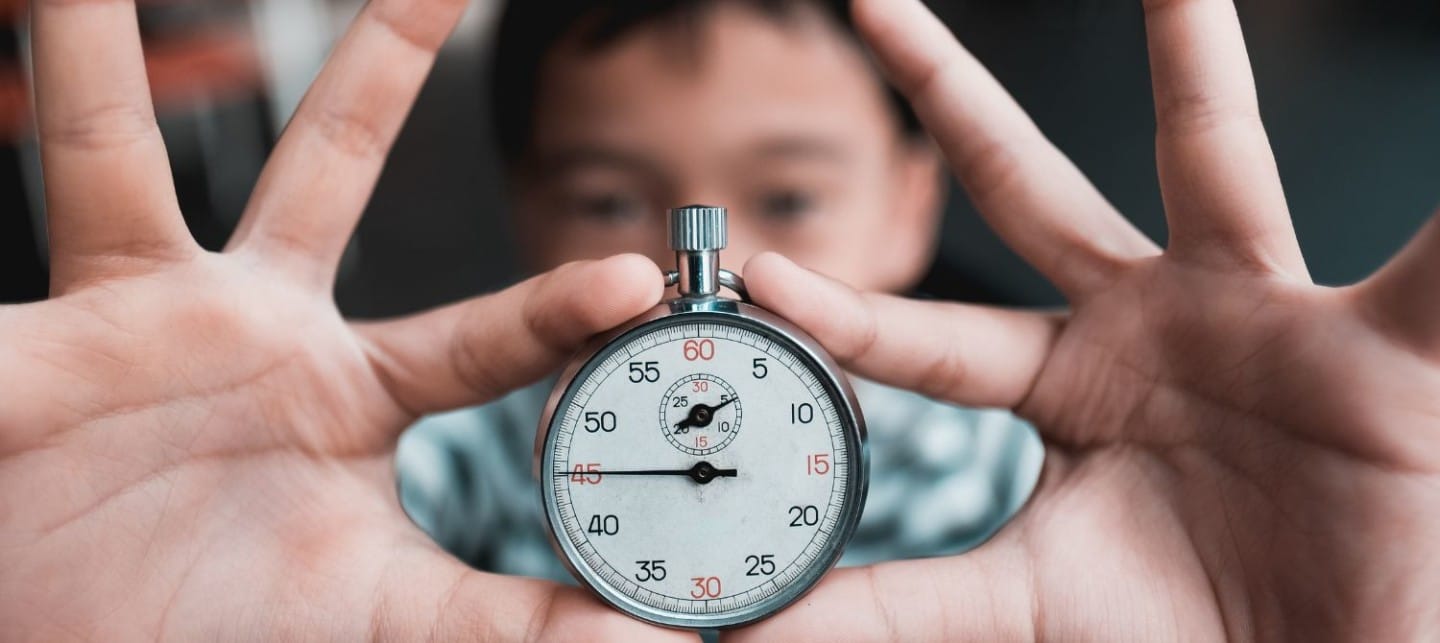 A child holding up a stopwatch, symbolizing perseverance and determination during challenging times