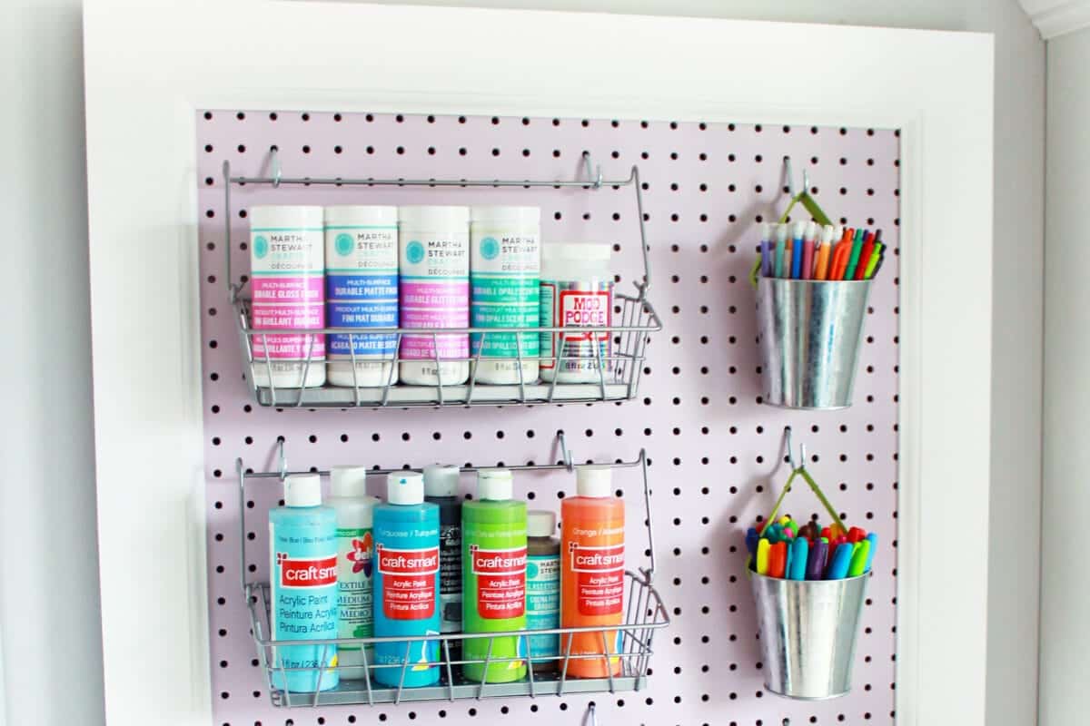 A pegboard with a basket of paint and markers, enhancing creativity and organization in the play area