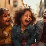 Three joyful children smiling in front of a building. They seem to be having a great time