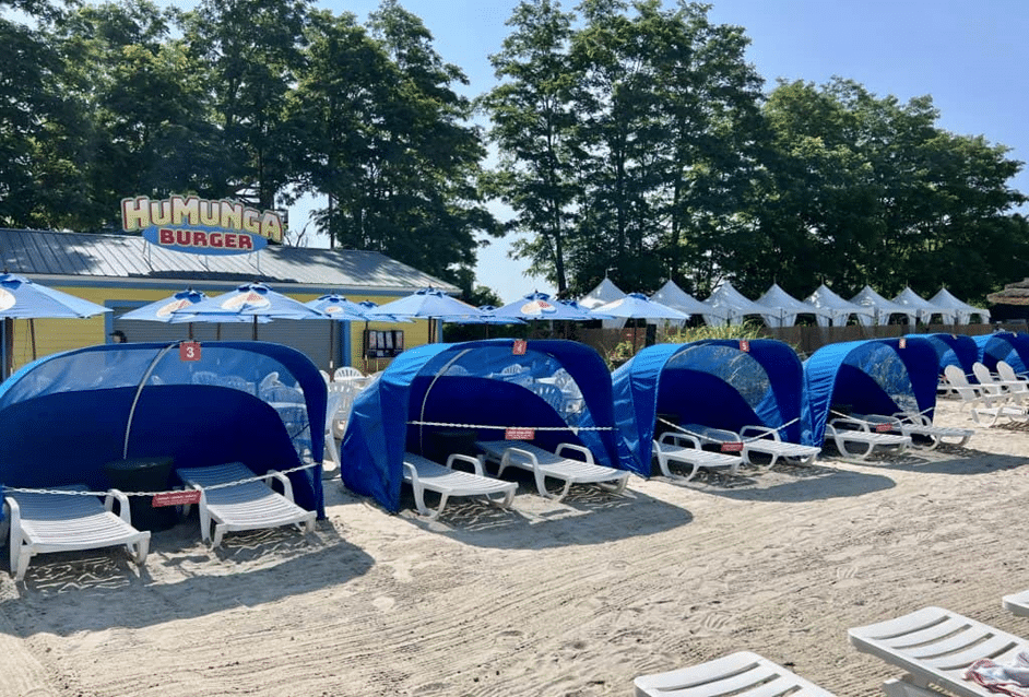 Beach umbrellas and chairs set up on the sand, with food options available at the waterpark
