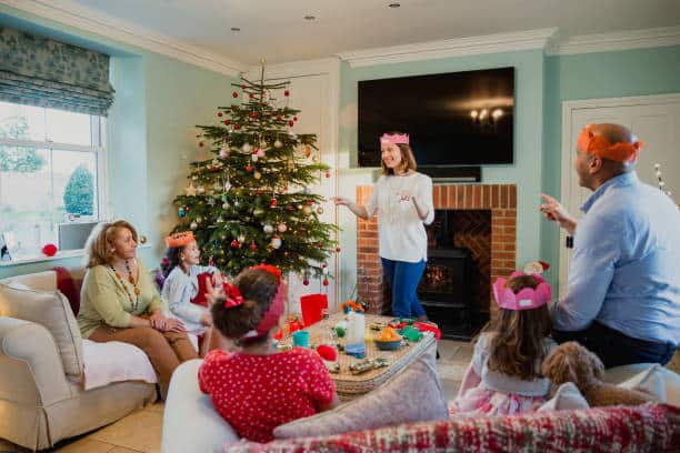 Family are playing charades at christmas time in the living room of their home. It's the mother's turn and everyone is trying to guess.