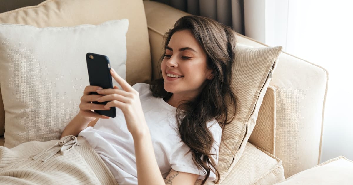 a girl lying on couch and looking at her mobile phone