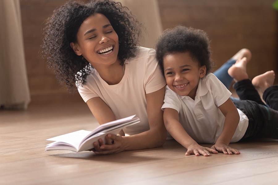 Smiling black mom and little son have fun reading