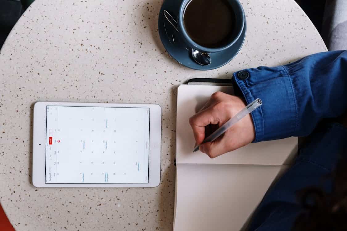 Free Person Holding Pen and Checking Calendar on Tablet Stock Photo