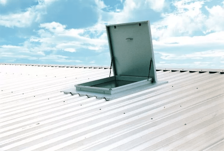 A photograph of a weathered metal roof hatch set